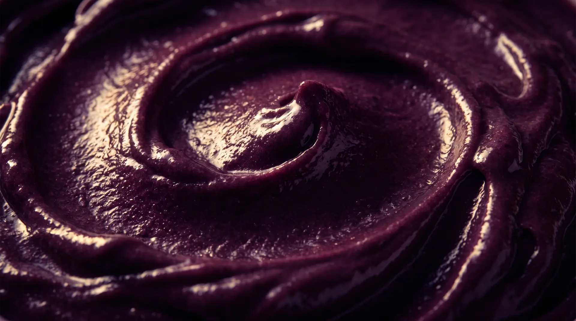 Makroaufnahme der tiefvioletten Açaí-Creme mit glänzender, wirbelnder Oberfläche